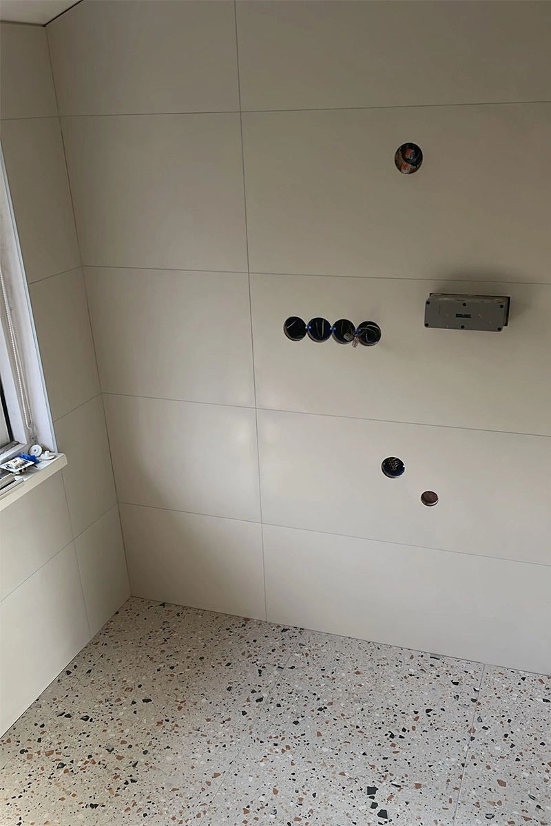 Frisse badkamer met witte wandtegels en stijlvolle vloer, inclusief toilet, verzorgd door VDB Tegelwerk.